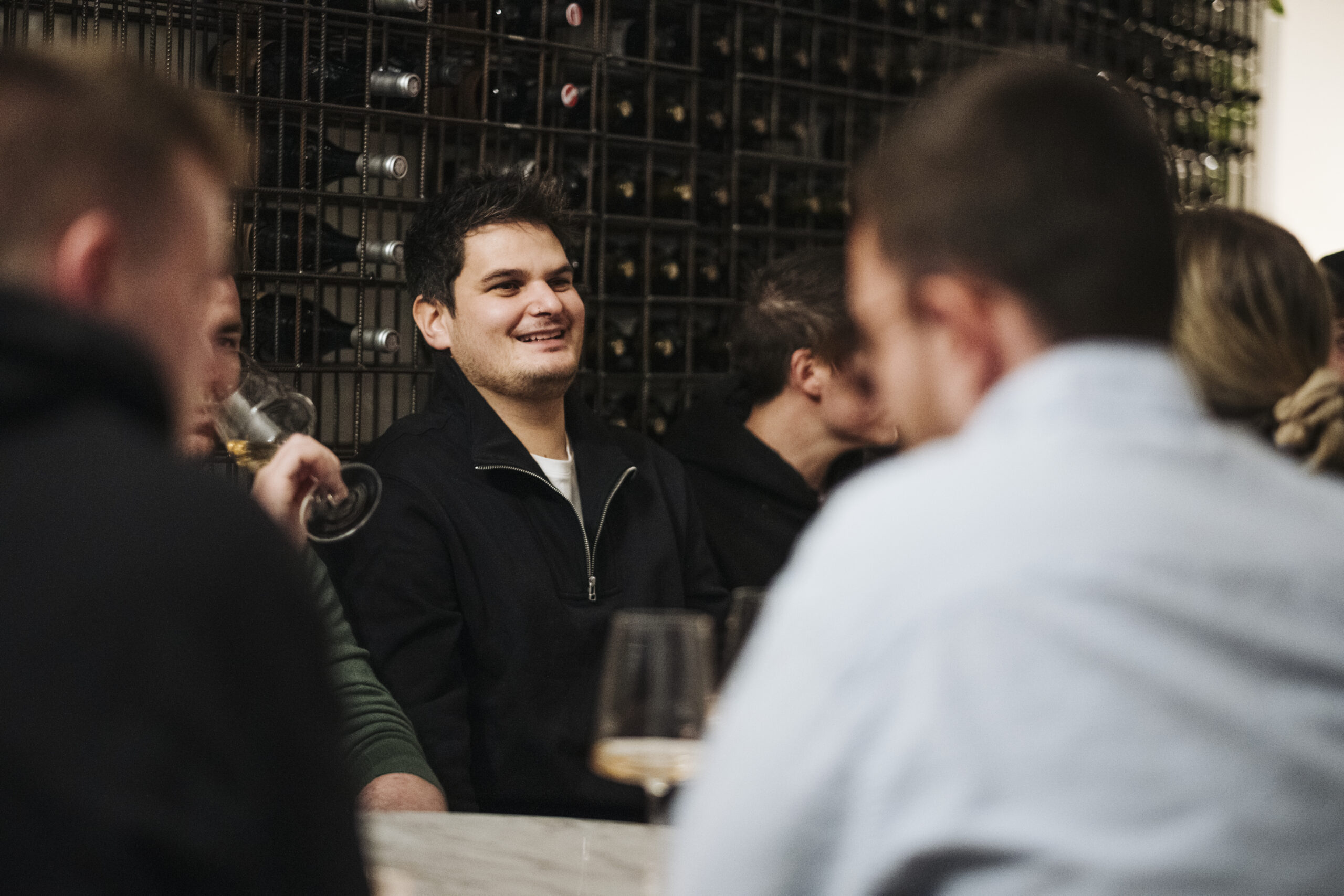 Junus lächelt vor Gruppe bei einem Vinum Voyage Weinabend